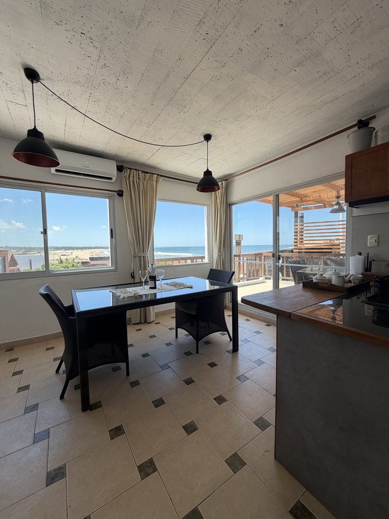 Comedor con el ventanal abierto a la terraza y al mar