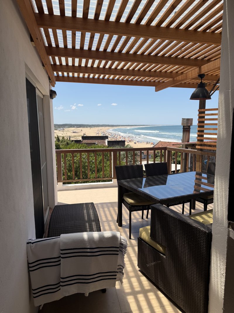 Terraza bajo la pérgola con reposera y mesa, mirando a la playa de La Pedrera