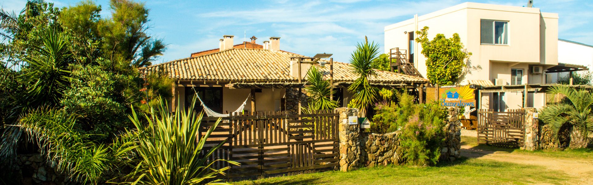 El frente del complejo Bungalows Aguazul, con el cartel de entrada y el portón de madera