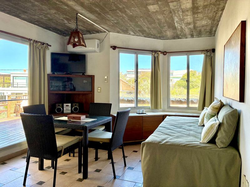 Living comedor con televisor, mesa y ventanales